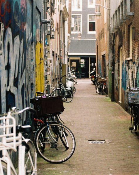 Steeg in Amsterdam met fietsen tegen muren vol met graffiti en stickers